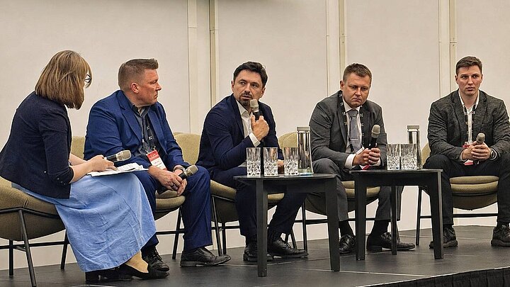 naukowcy siedzą za stoliczkiem i dyskutują
